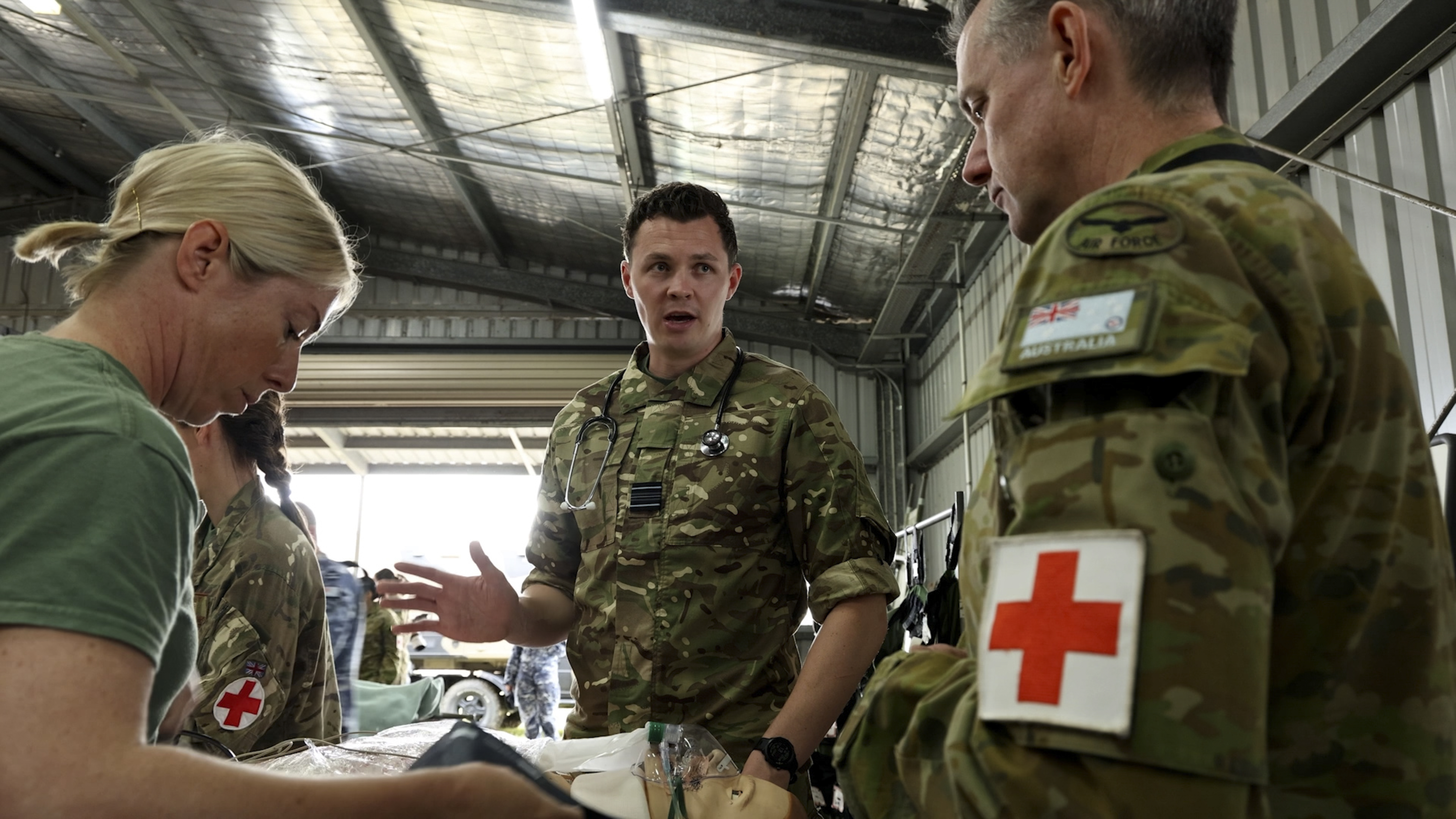 Two RAF personnel talking to an Australian Air Force medical service person.