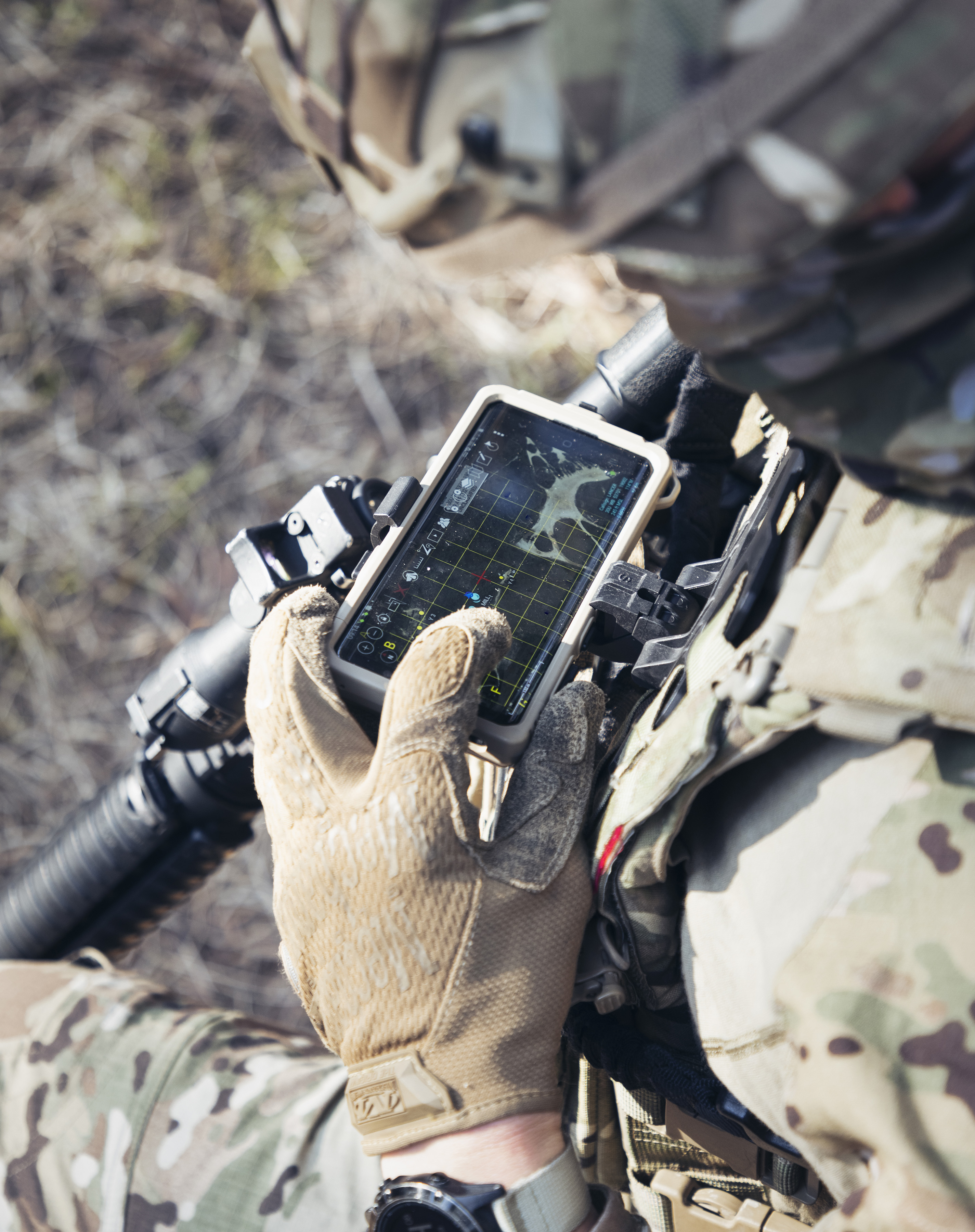 A British service person looking down at a chest-mounted phone for mapping.