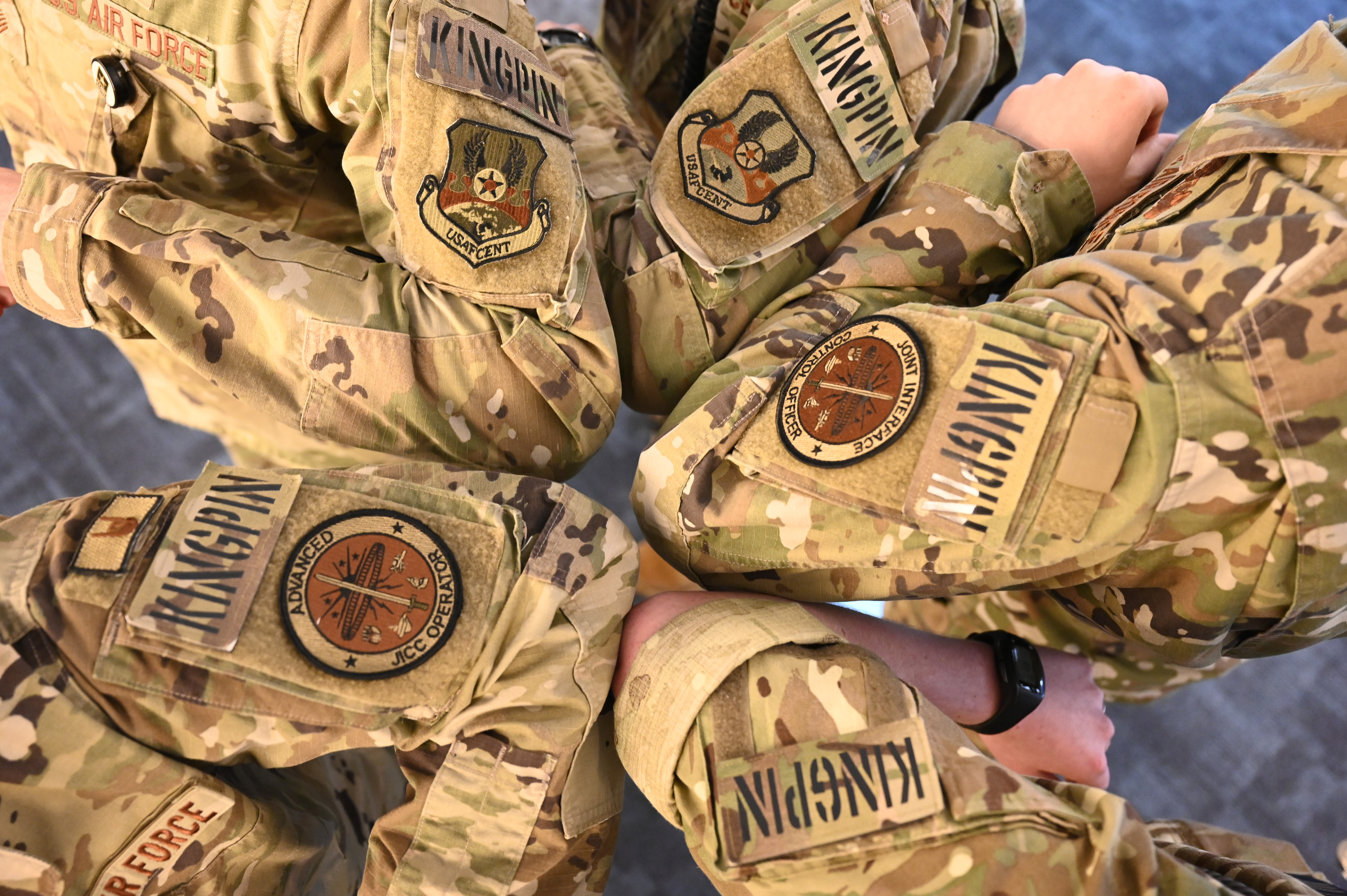 Five servicepeople's arms, with KINGPIN patches worn