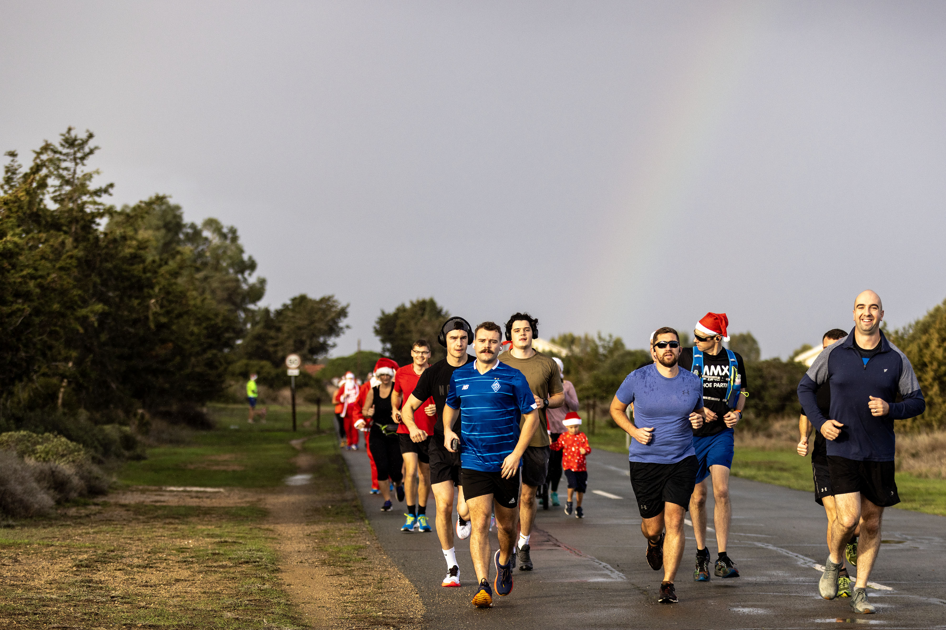 Group of people running down a road as part of the fun run, with a rainbow in the background.