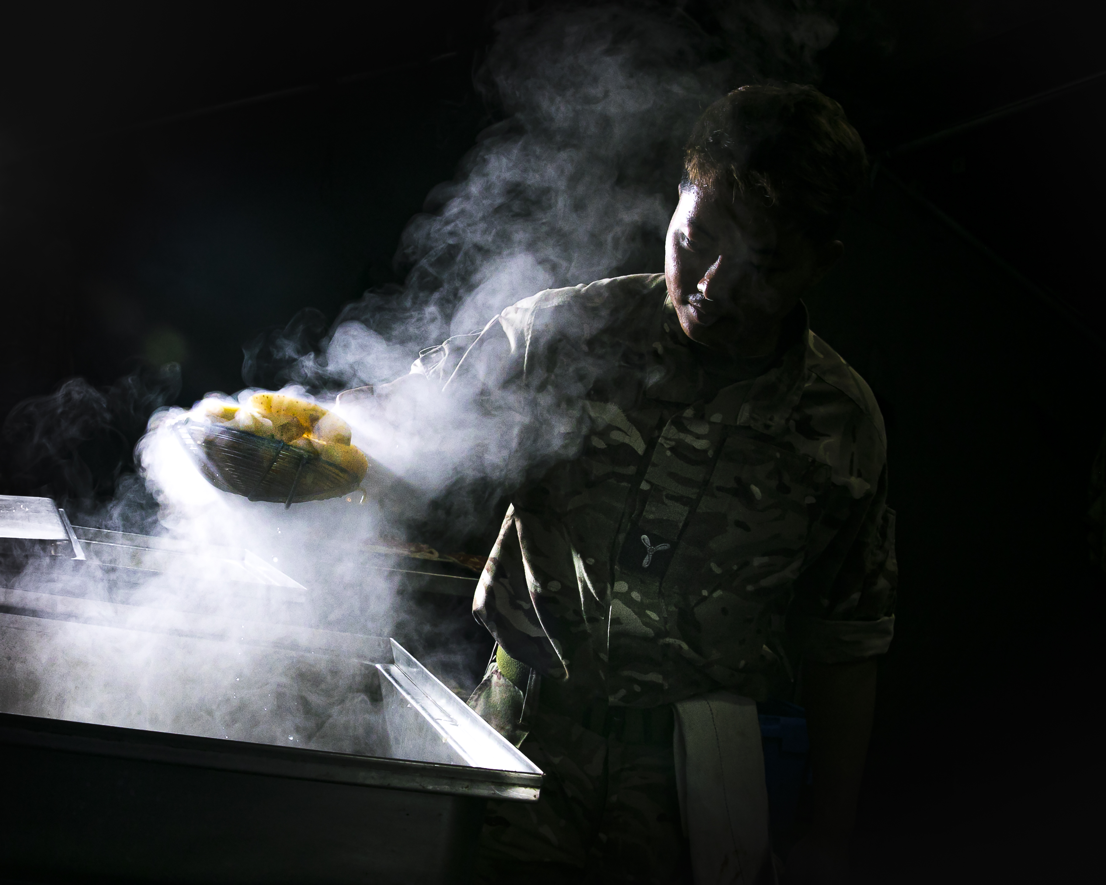 A chef from 3MCS cooking a meal in a field kitchen while on exercise.