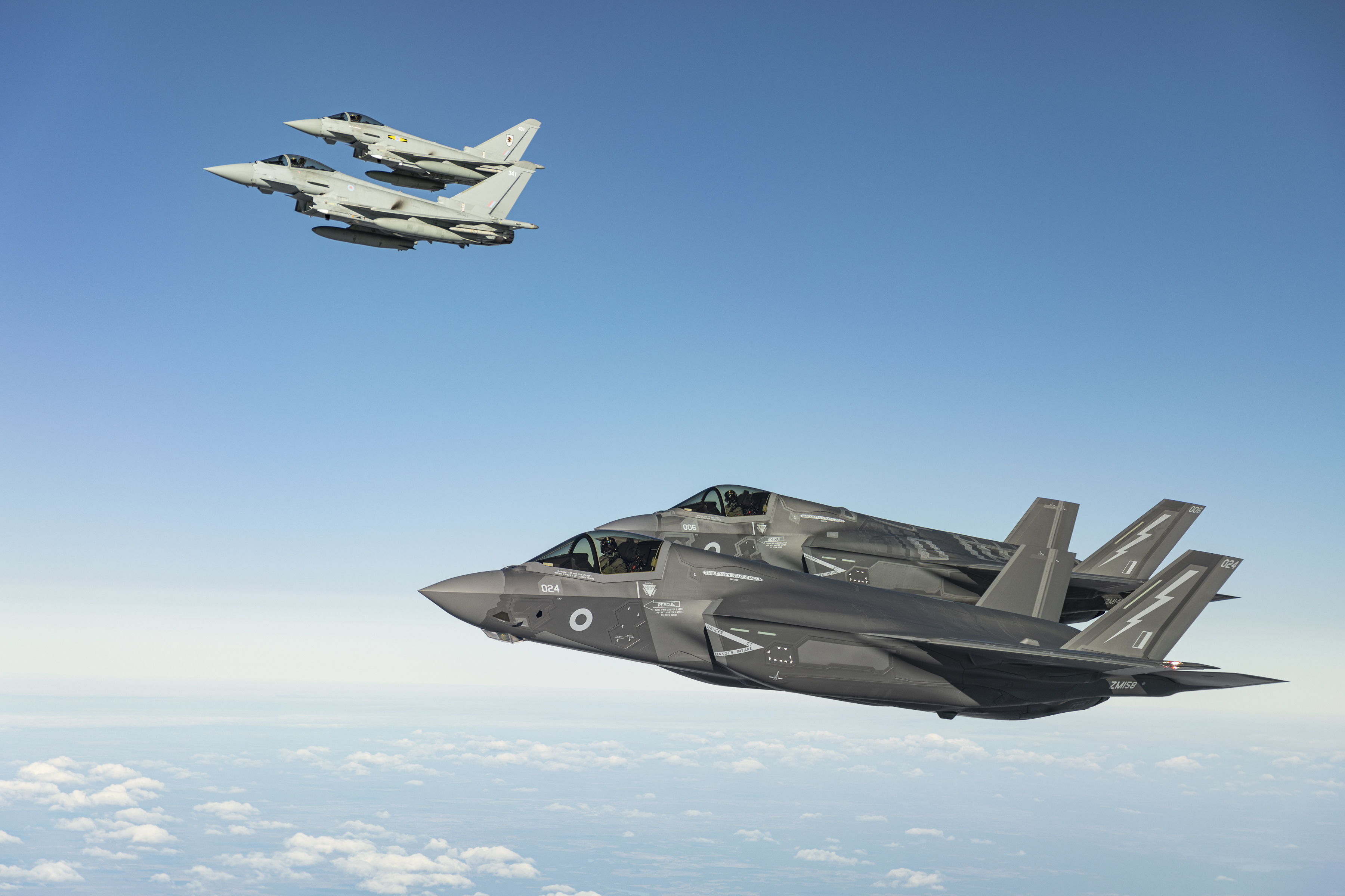 Four aircraft flying in formation through blue skies.