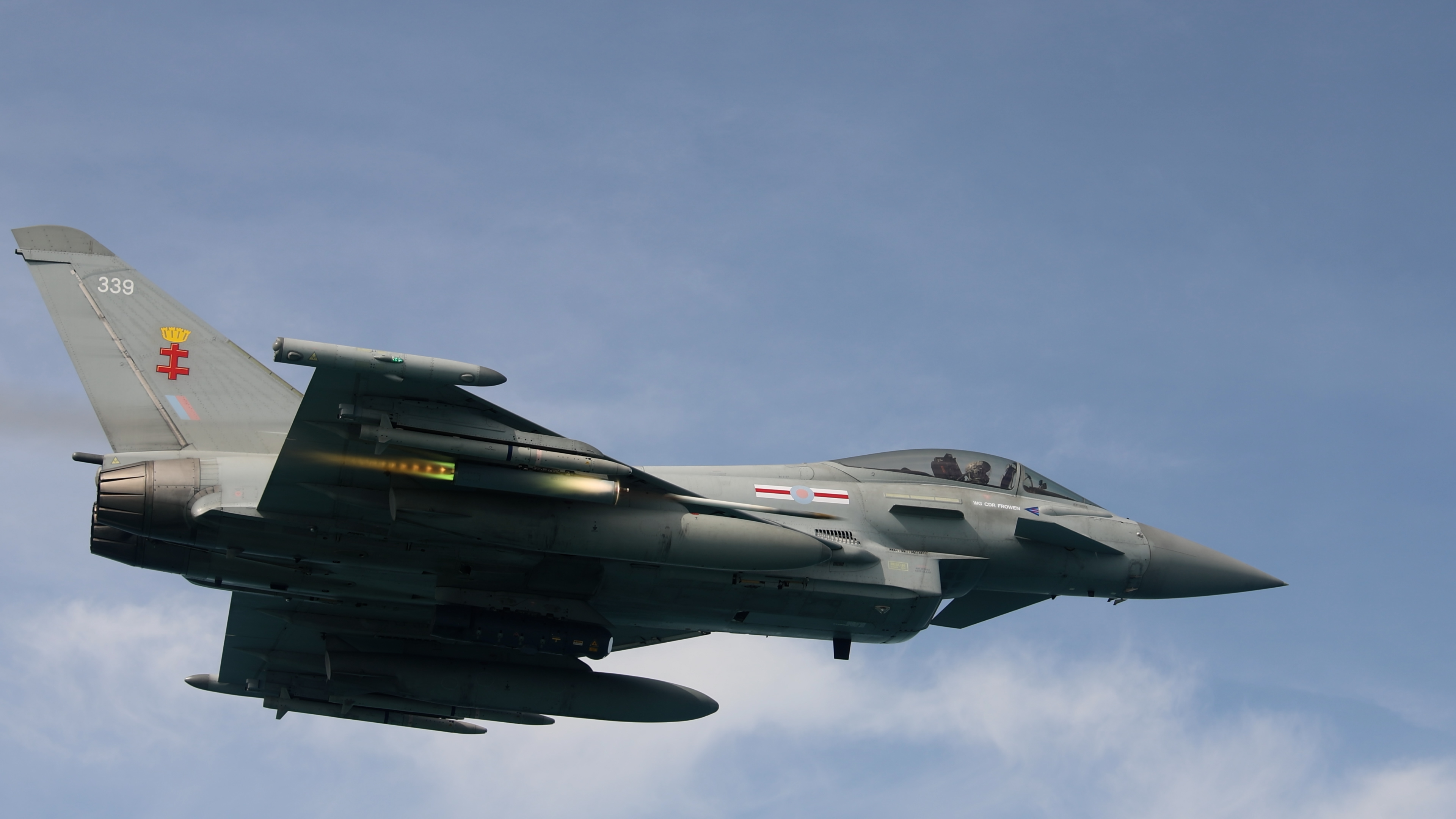 RAF Typhoon aircraft in flight releasing an APKWS-guided rocket, visible as a bright streak beneath the wing.