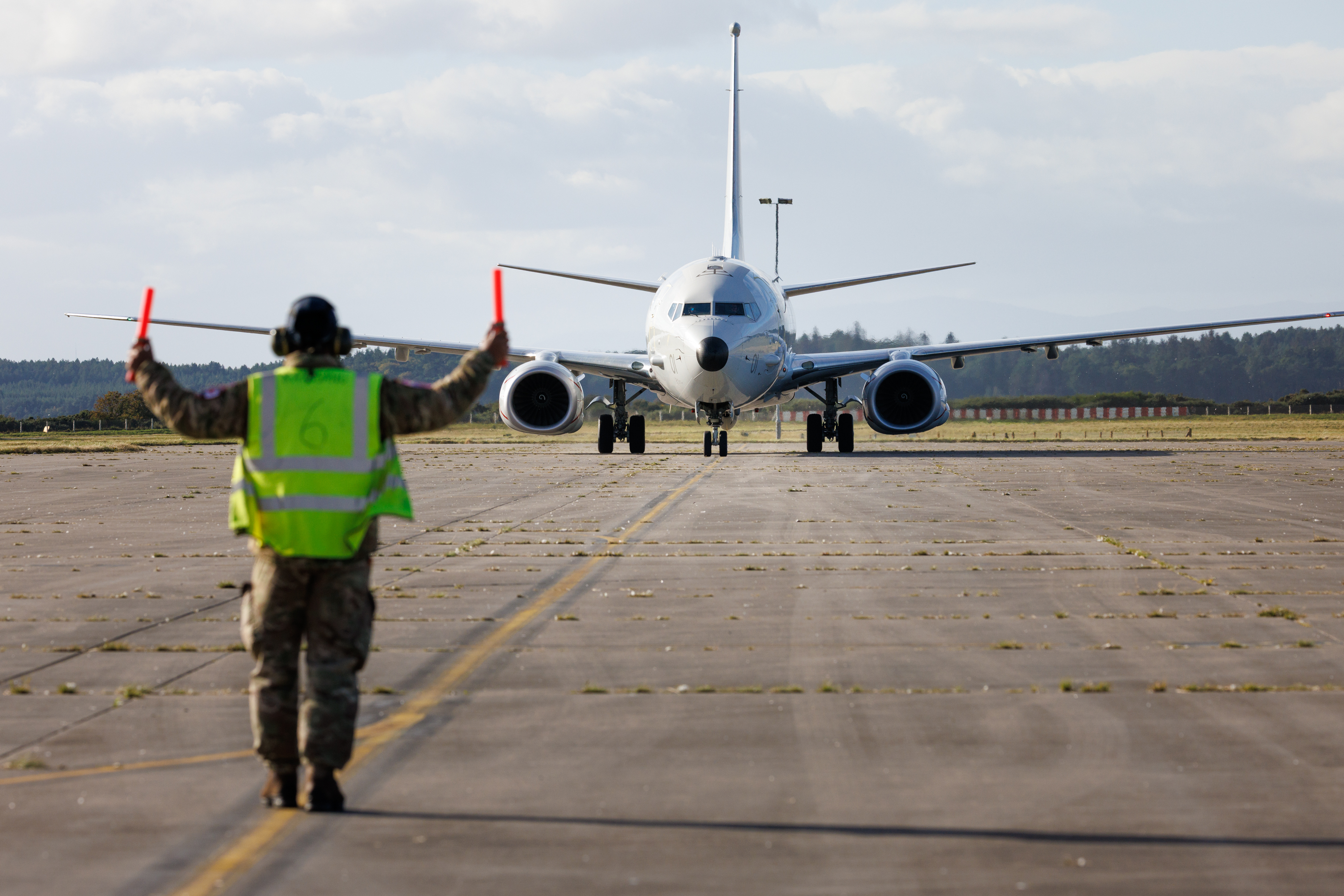 An air traffic controller guiding an RAF Poseidon along the runway at RAF Lossiemouth.