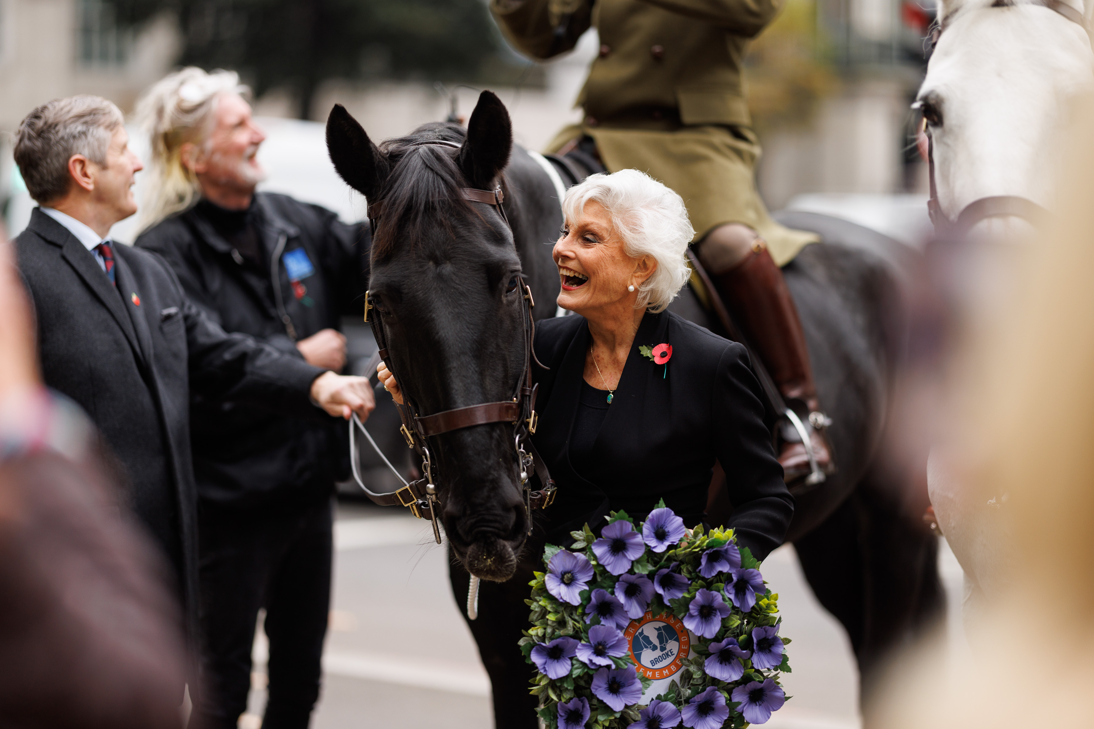 Angela Rippon laughing at the event whilst holding a wreath.