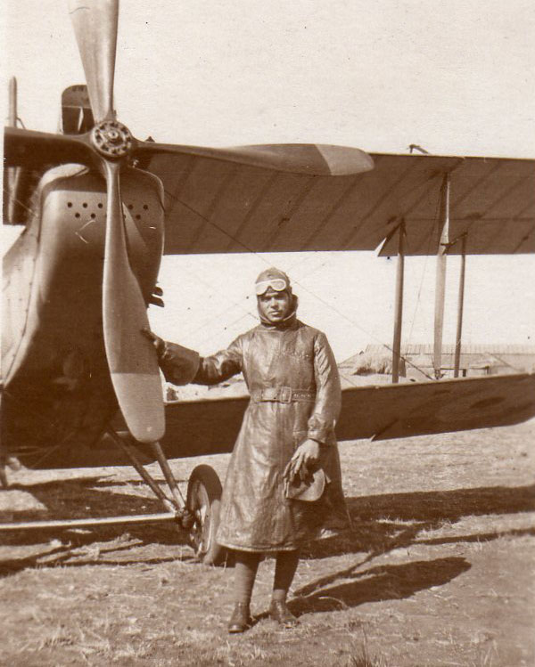 Black and white photo of personnel standing by the front of a Spitfire.