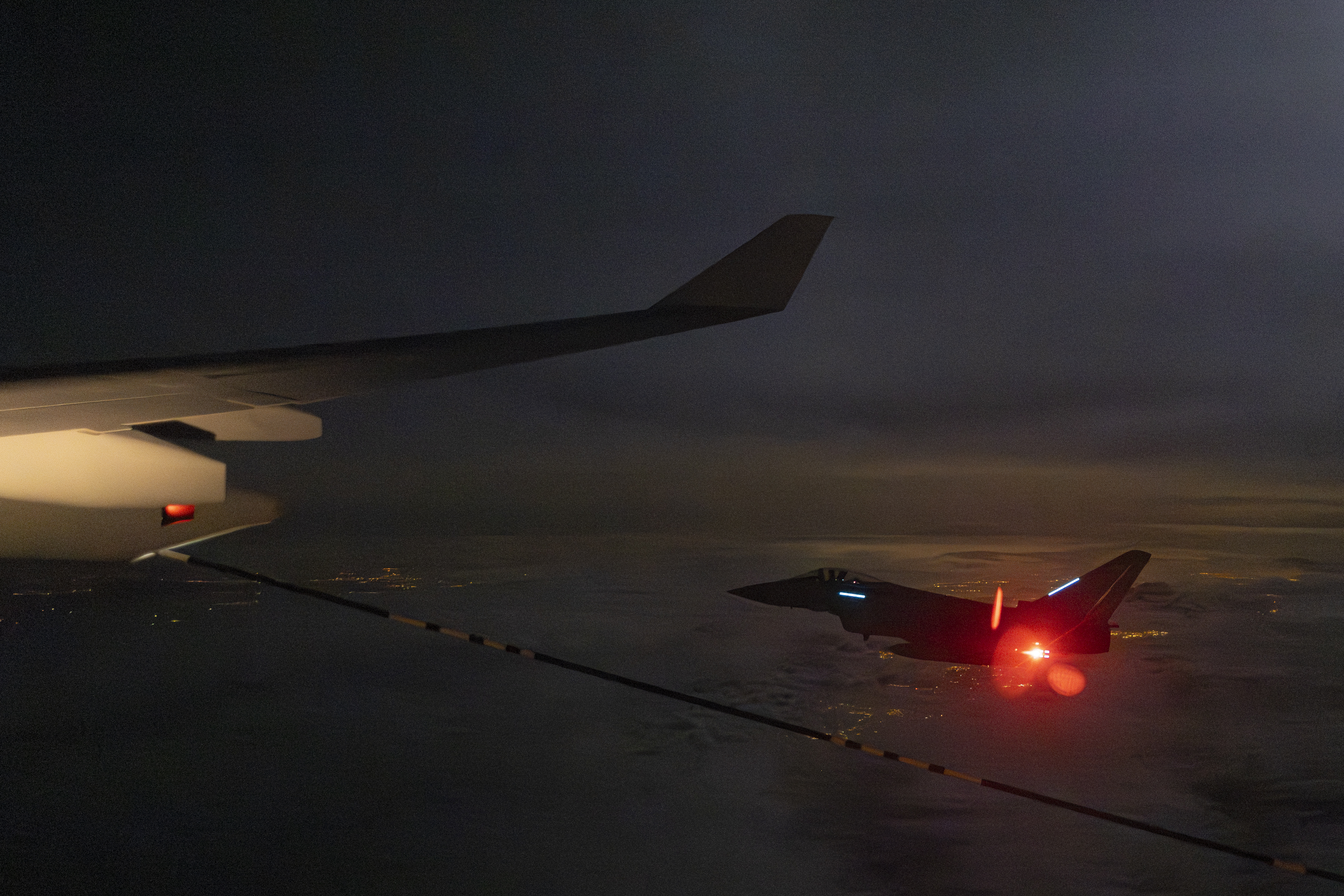 A British Eurofighter Typhoon being air-to-air refuelled by Voyager at night.
