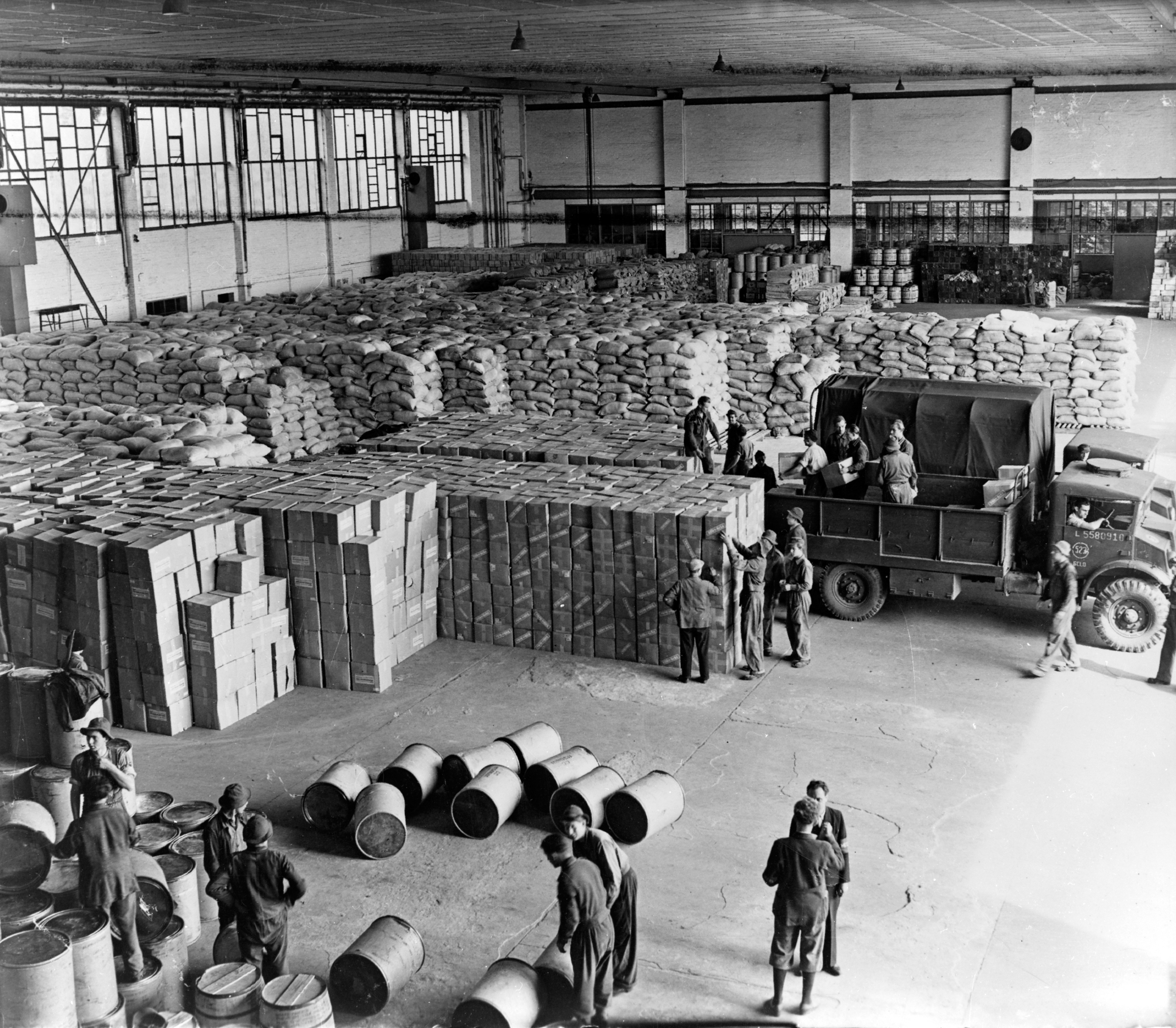Black and white image shows a warehouse full of aid with people working.