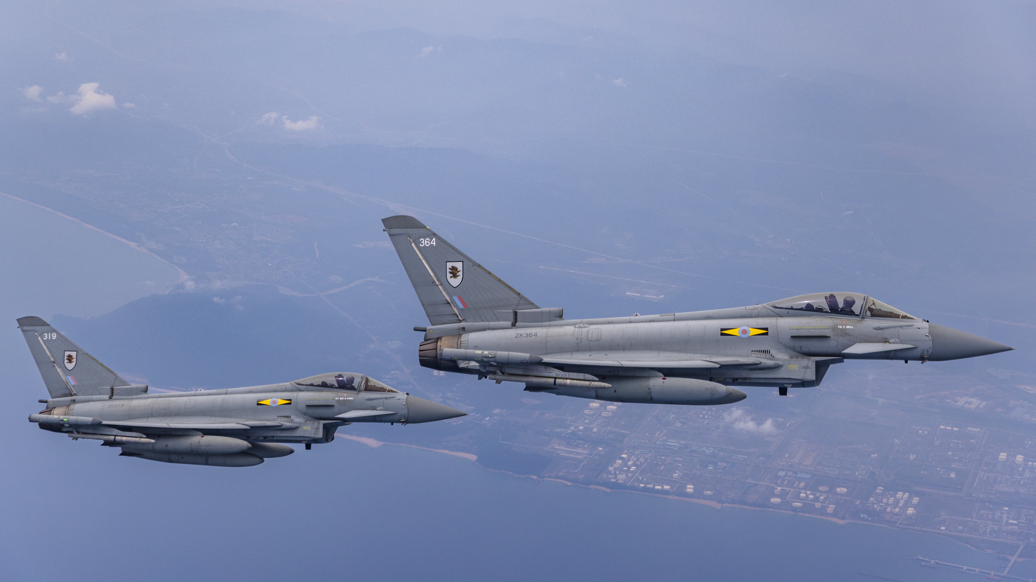 2 military aircraft flying above coastal area
