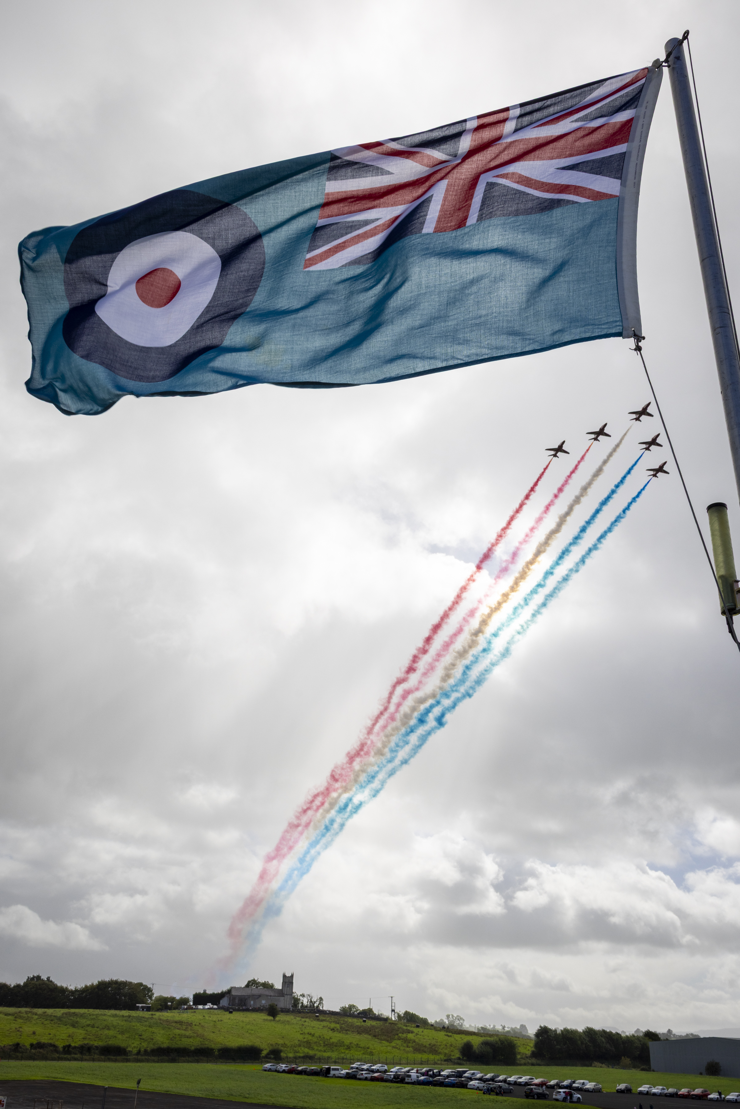 The ensign of the Royal Air Force, with a Red Arrows display flypast in the background.