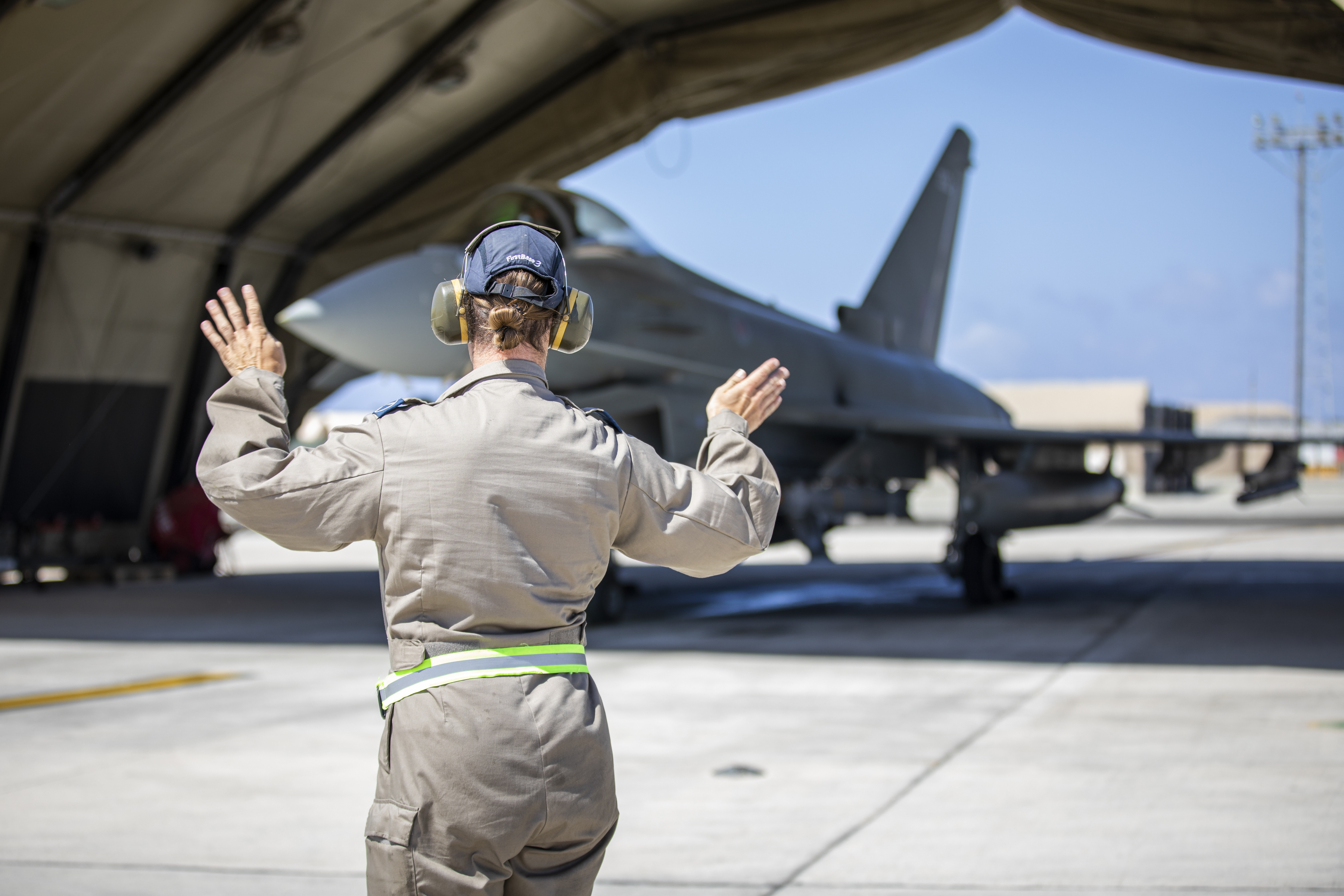 RAF personnel guiding an aircraft on the runway.