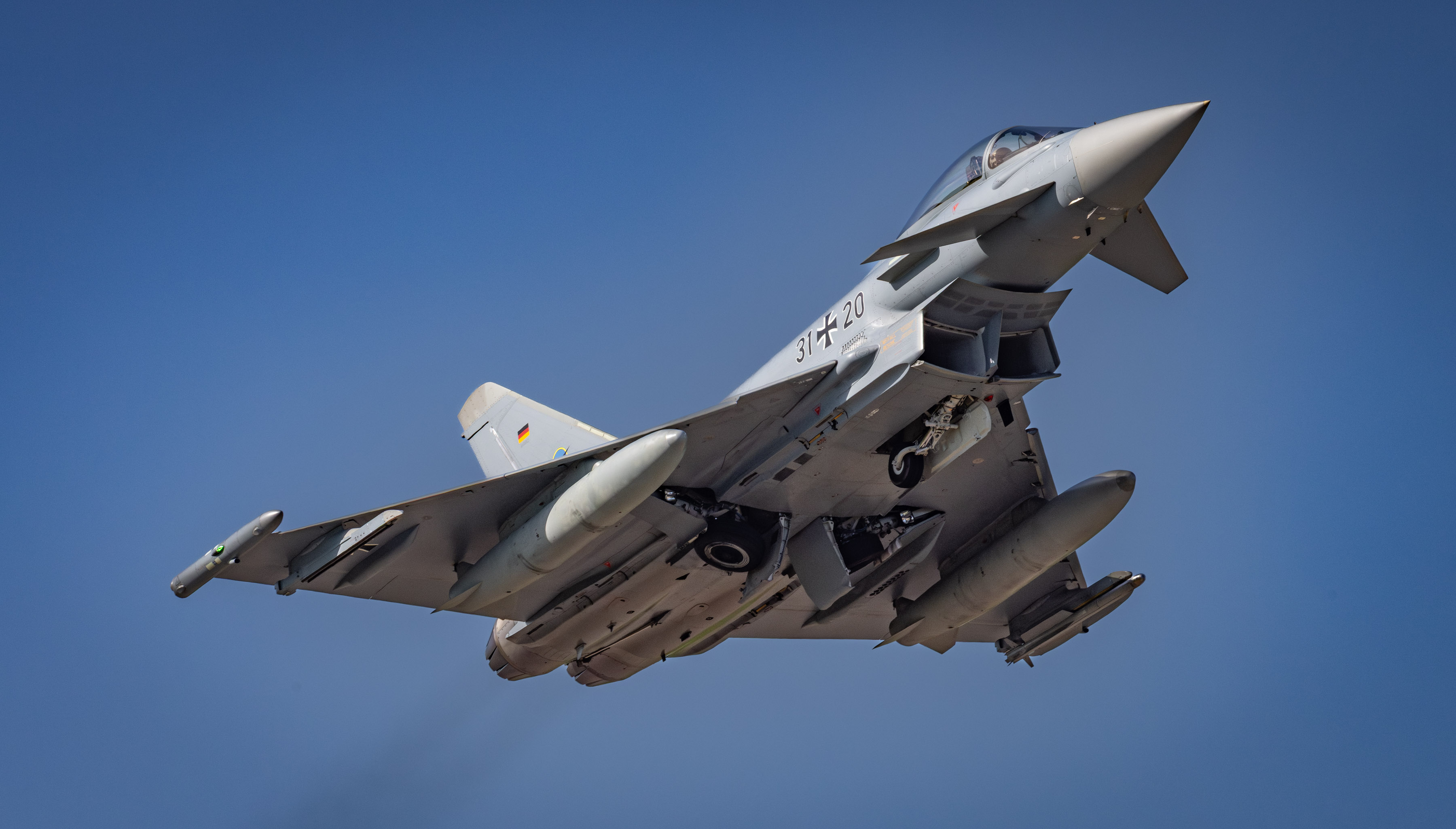 A Luftwaffe Typhoon taking off through blue skies, seen from underneath.
