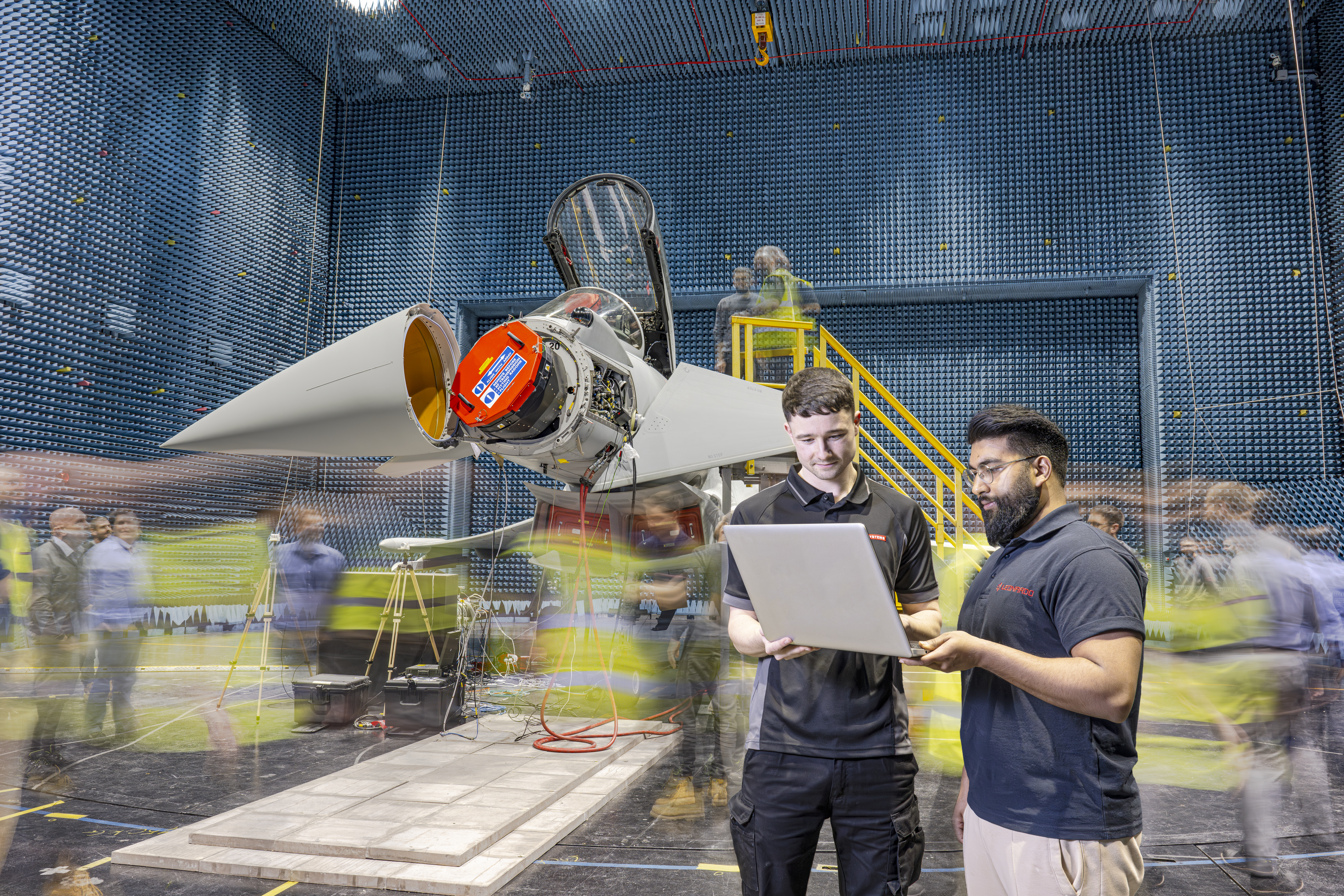 A long-exposure shot of the warehouse where ECRS Mk2 is being fitted to an RAF Typhoon, showing Leonardo and BAE Systems technicians and engineers hard at work.