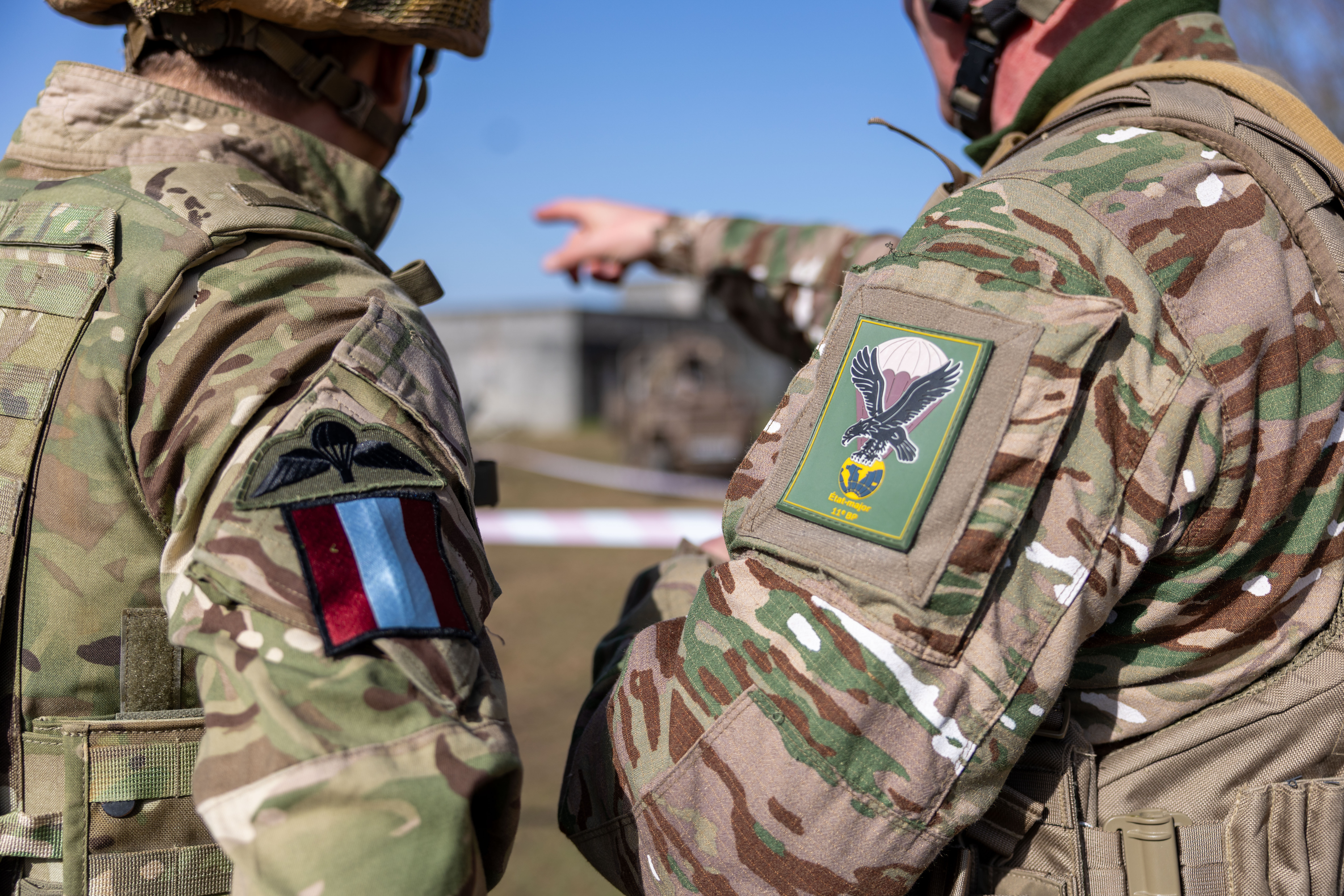 A British and French paratrooper standing side-by-side. The focus of the image is on their patches.