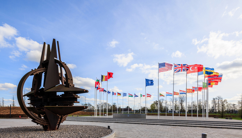 The NATO Star with NATO member flags in the background.