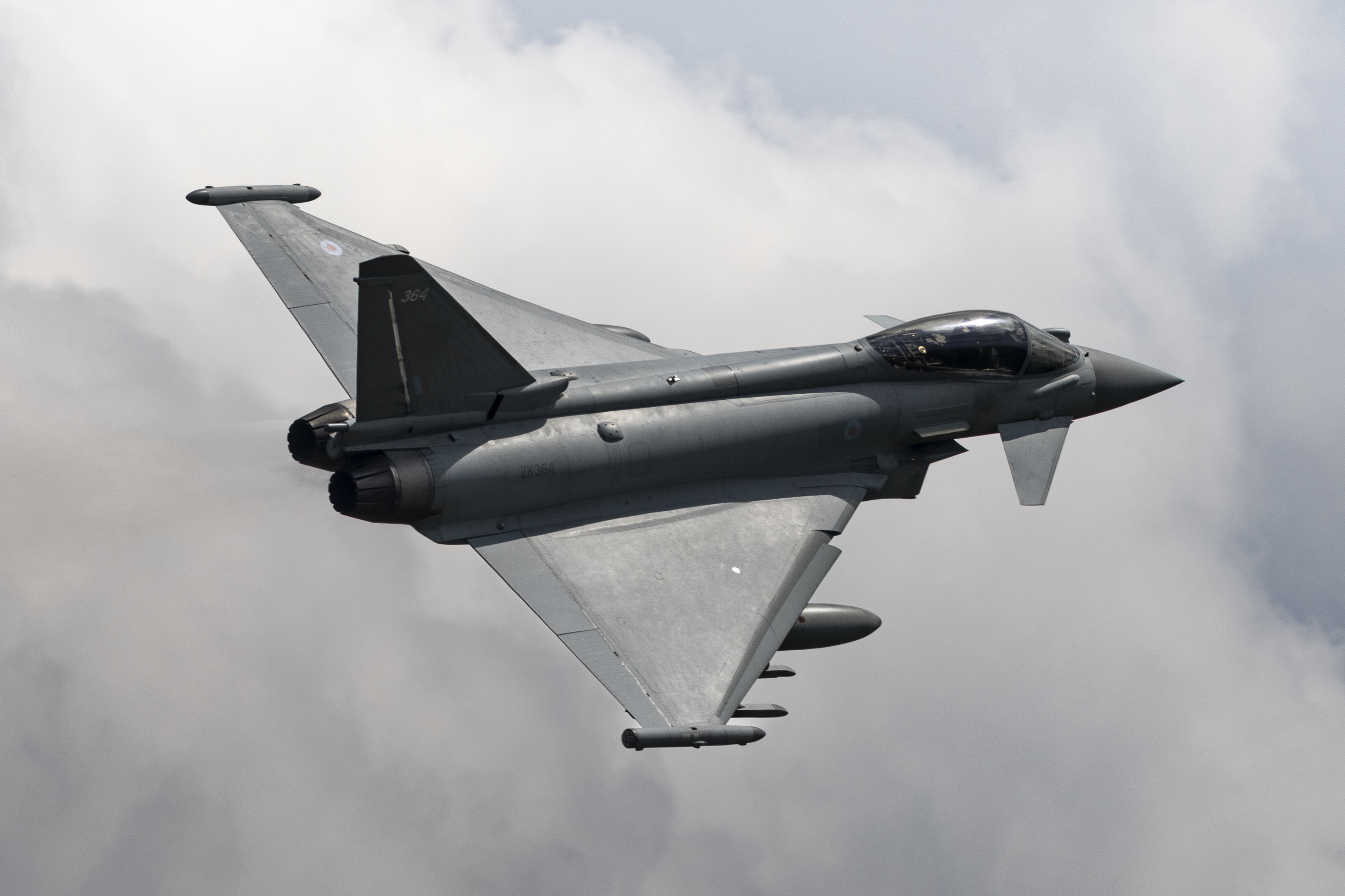 An RAF Typhoon in flight through cloudy skies.