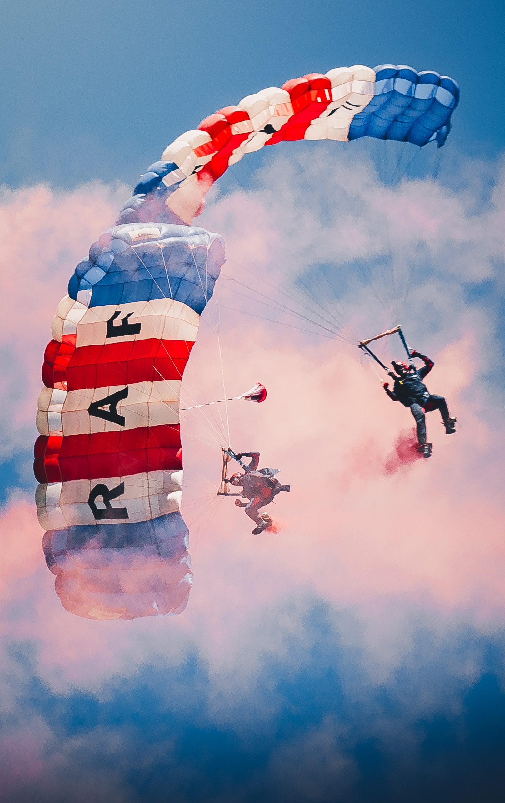 2 RAF parachutists landing amid red smoke