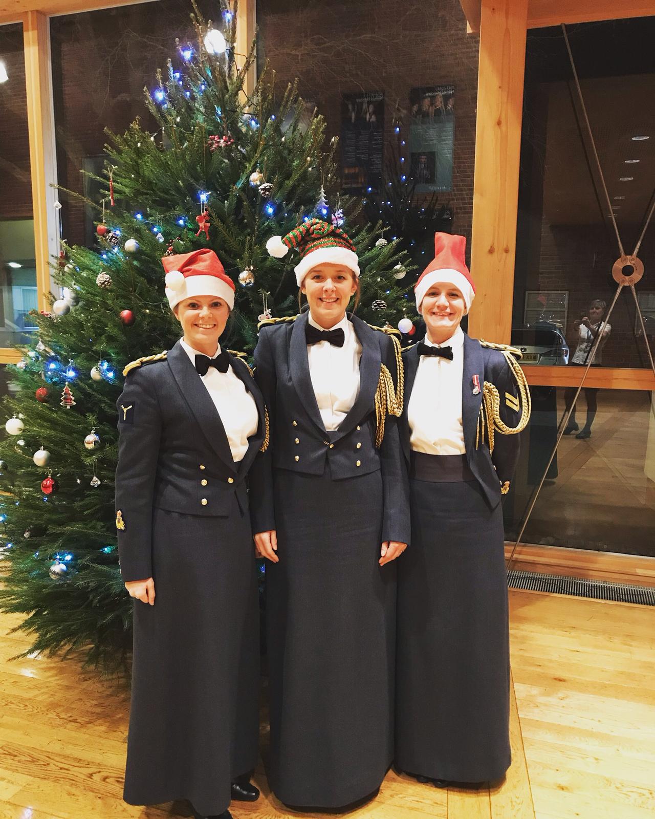 Three Musicians pose for the camera infront of a Christmas tree.