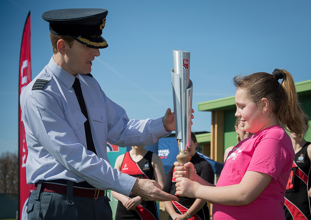 RAF Brize Norton Station Commander, Group Captain Tim Jones, having accepted the baton from the Netball team, passes it to Anna Lewis, to begin the families relay 