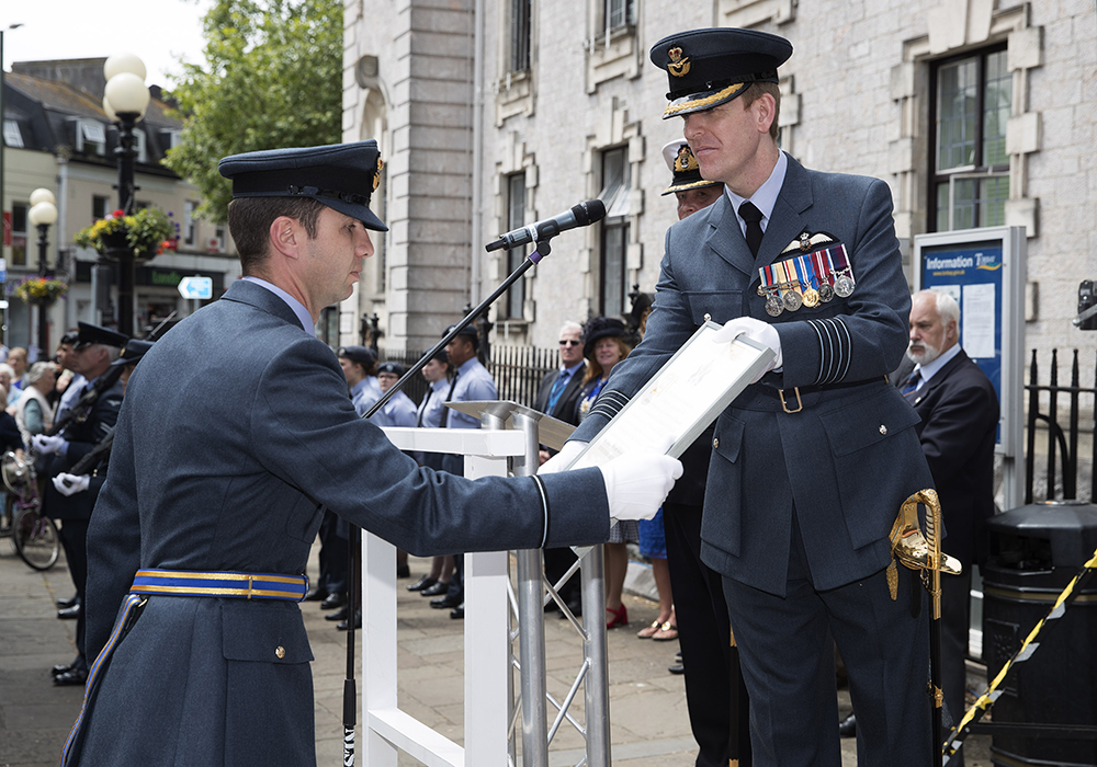 Group Captain Tim Jones, Station Commander, RAF Brize Norton, hands the Title Deed of Freedom to his Scroll Bearer, Flying Officer Richard Morris-Prewitt.
