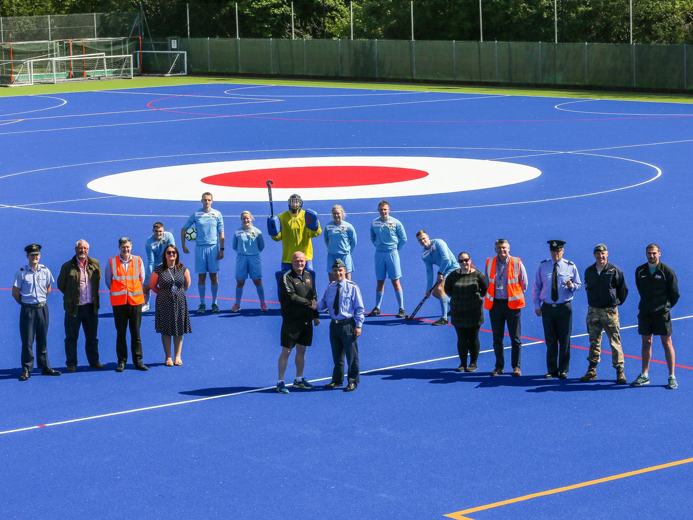 New AstroTurf pitch with station personnel standing near the centre which is the RAF roundel