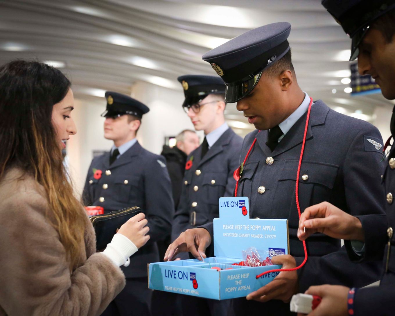 Airman with collection bucket and female donating money in it.