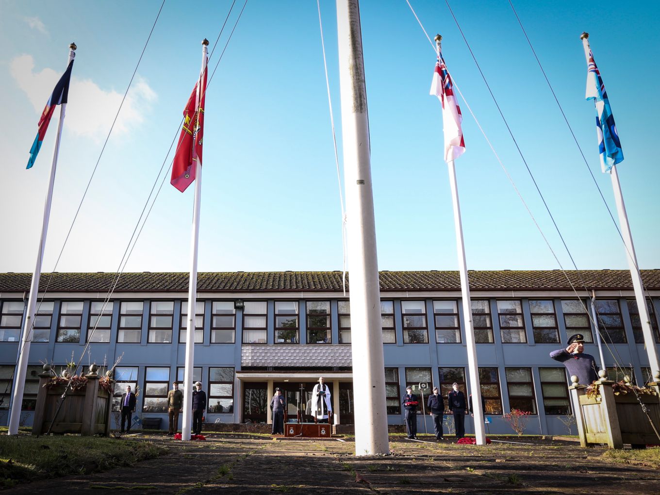 Military ensign flying with members of all three services