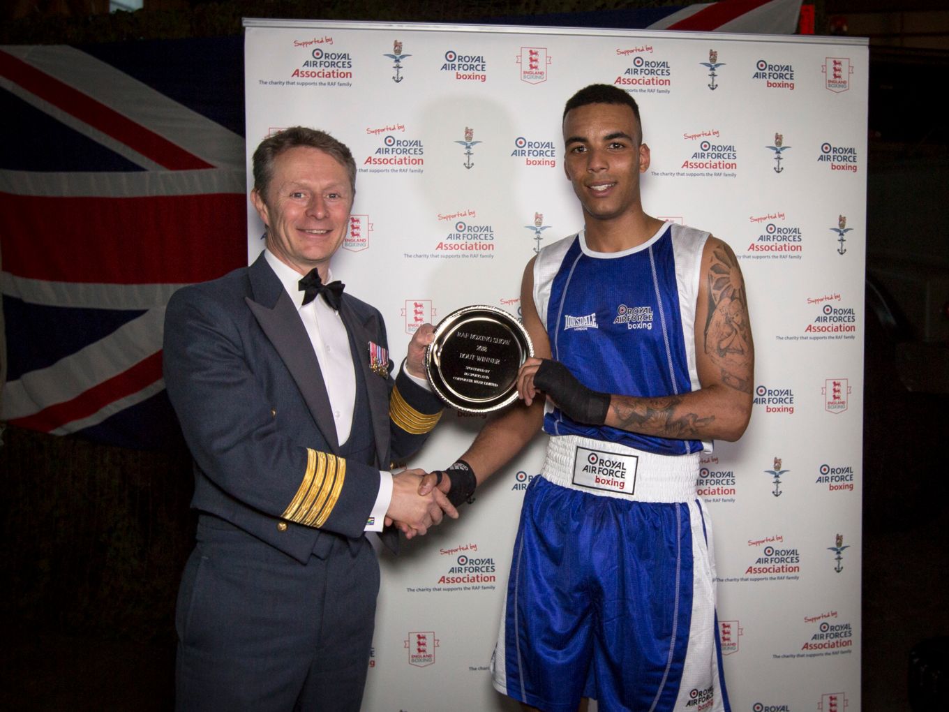 Group Captain Tony Keeling presents a trophy to the winner of the first bout, Senior Aircraftman Bright from RAF Leeming