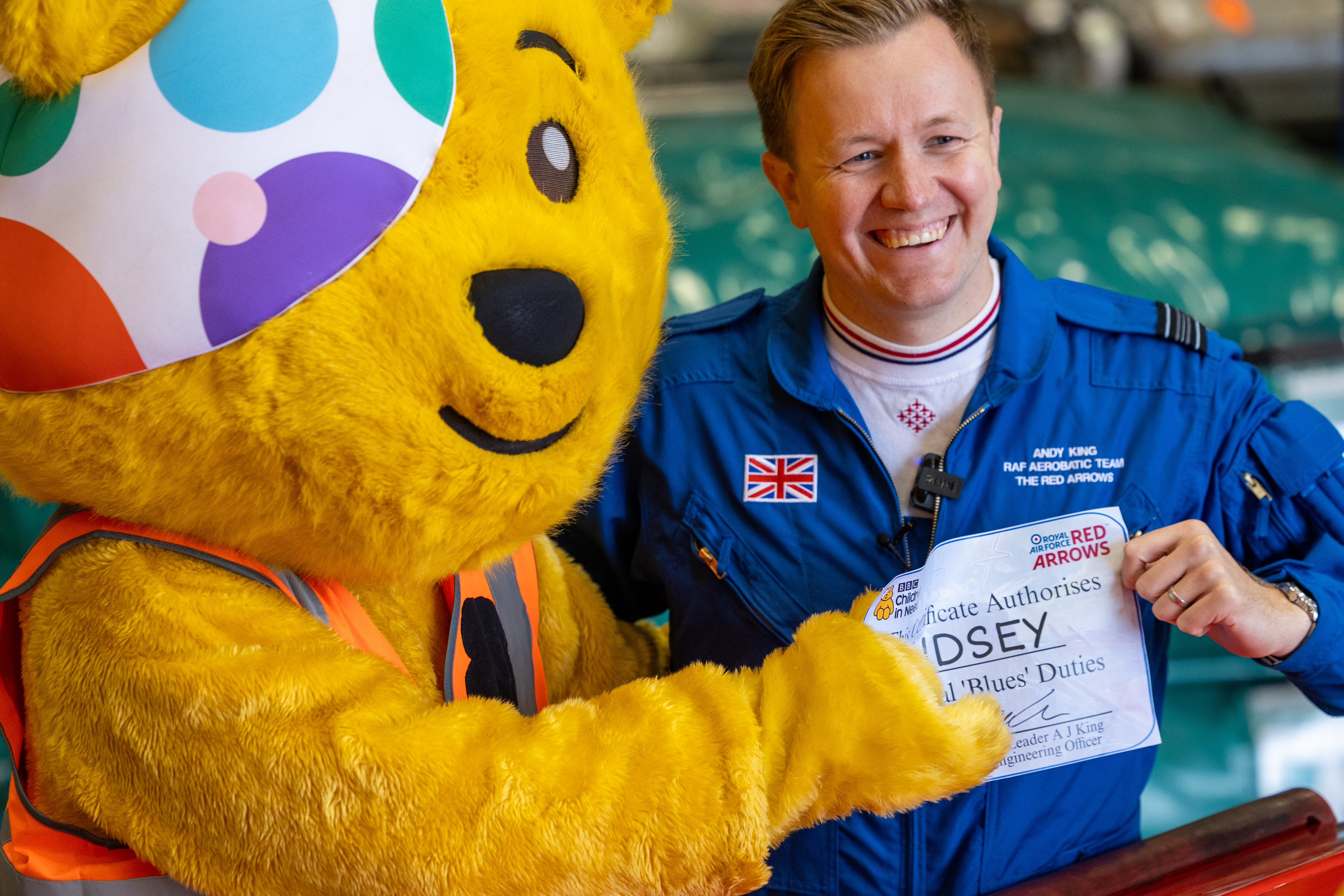 Pudsey is giving a certificate, confirming he's joining the Blues - the Red Arrows support team.