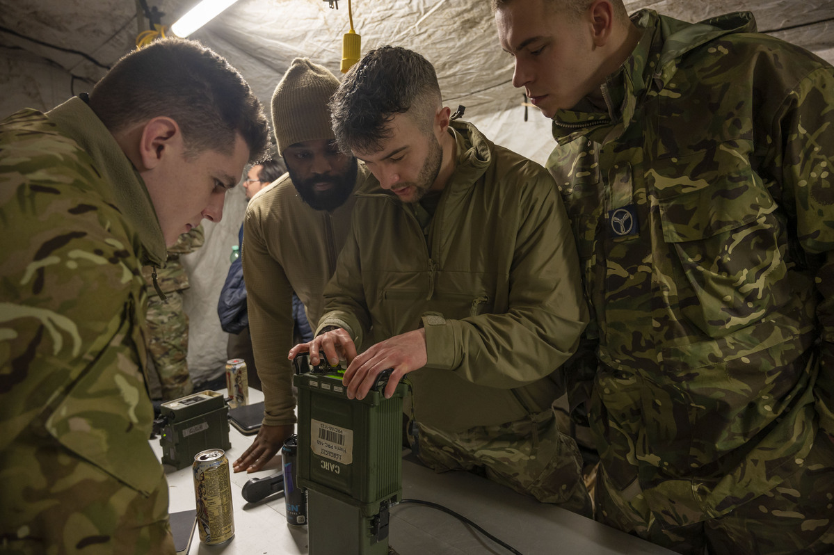 Group of four servicepersonnel working on a piece of equipment