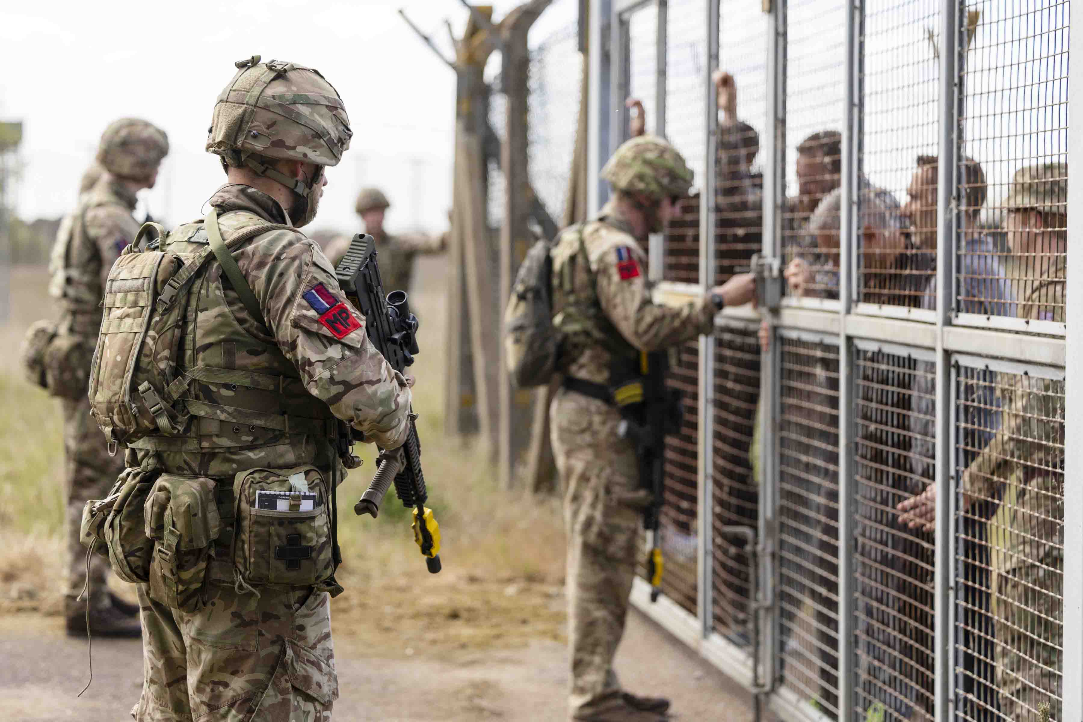 Armed RAF pers secure a perimeter whilst crowds (who are part of the ex) try to gain entry