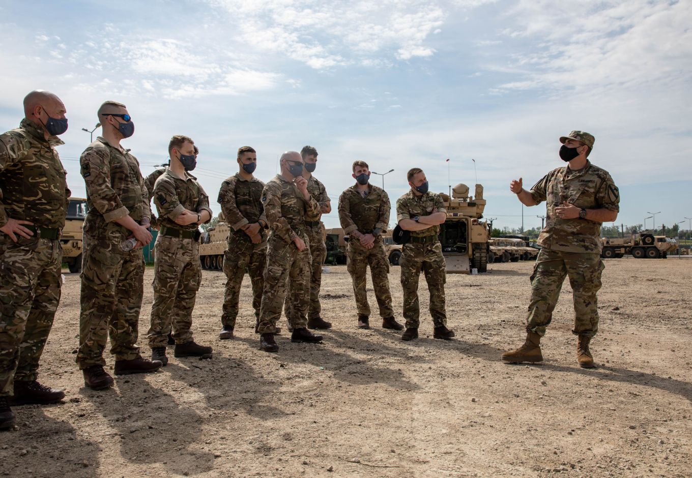 US Army and RAF Gunners stand in discussion.