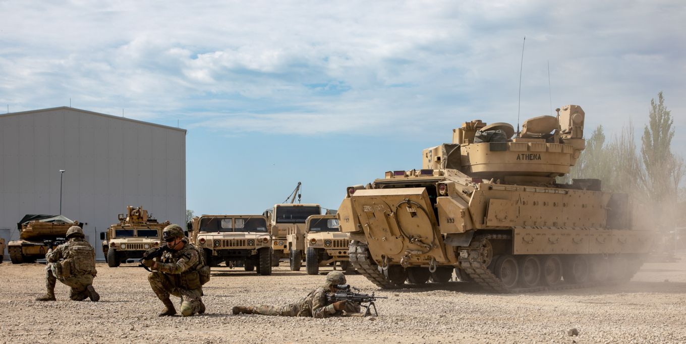 US Army’s Bradley Infantry tank and other vehicle, and personnel with rifles on exercise.