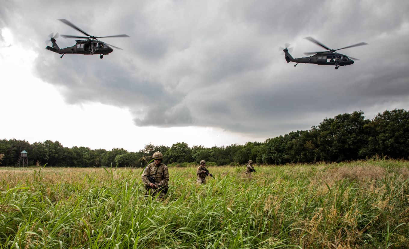 Two US Army Black Hawk helicopter above three RAF Regiment Gunners.