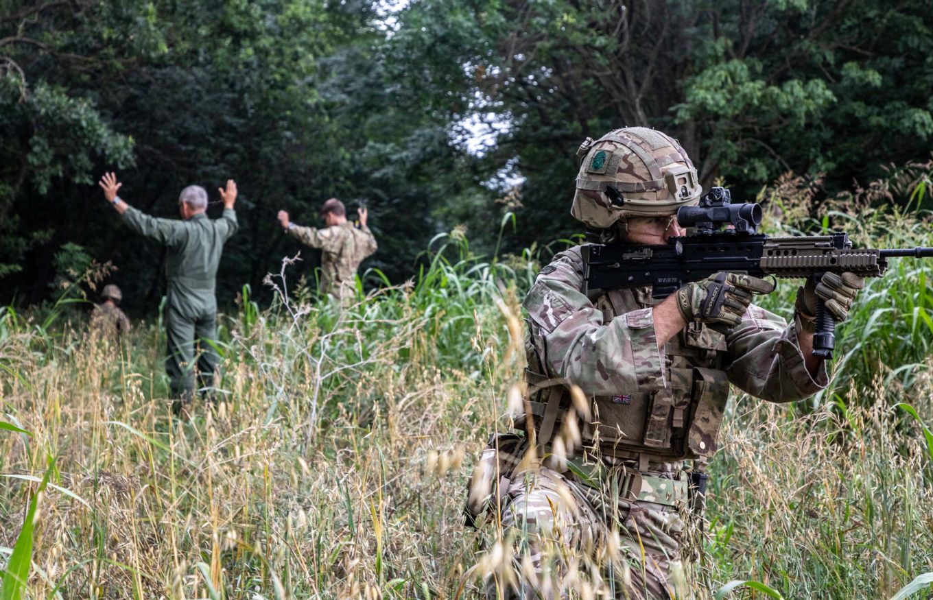RAF Regiment Gunner with personnel in the background.