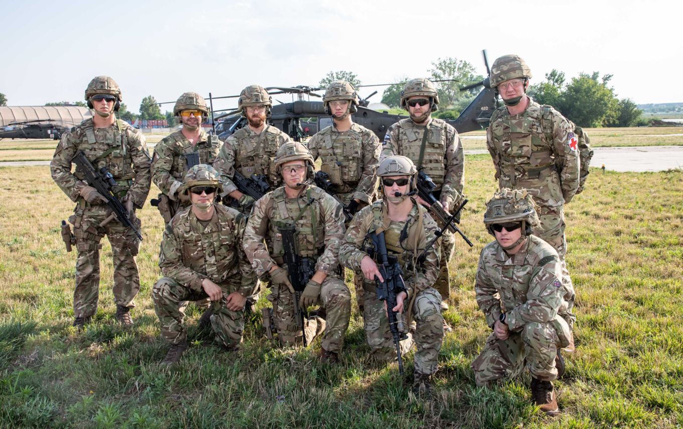 RAF Regiment stand with rifles and US Army Black Hawk helicopter in the background. 