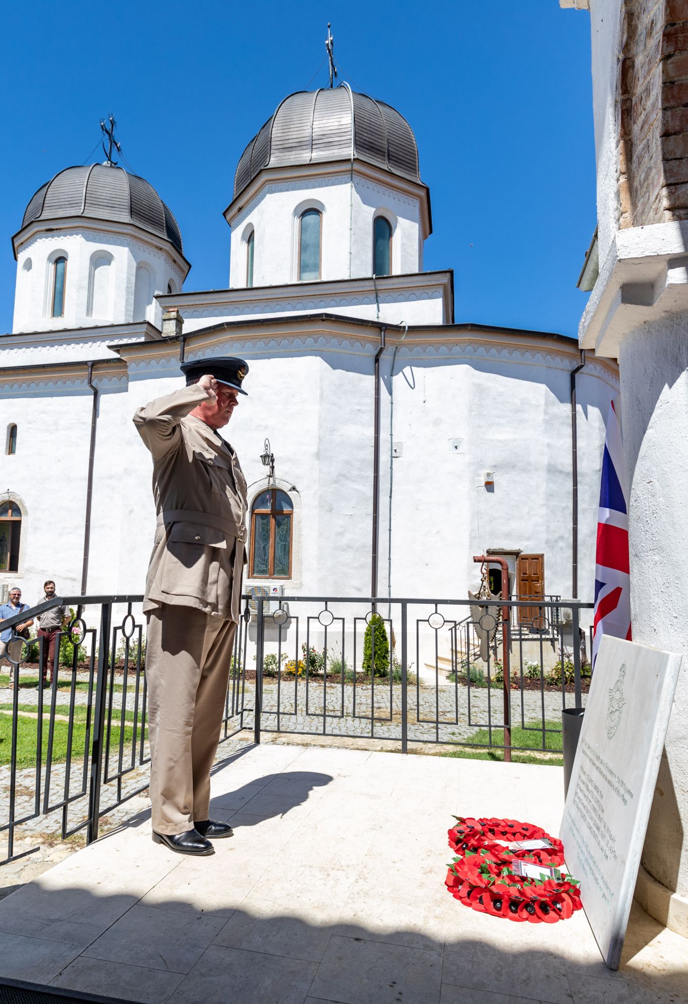 Personnel saluting Memorial and poppy wreaths.
