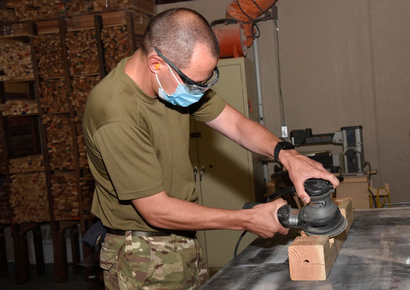Personnel using woodwork equipment in the workshop.