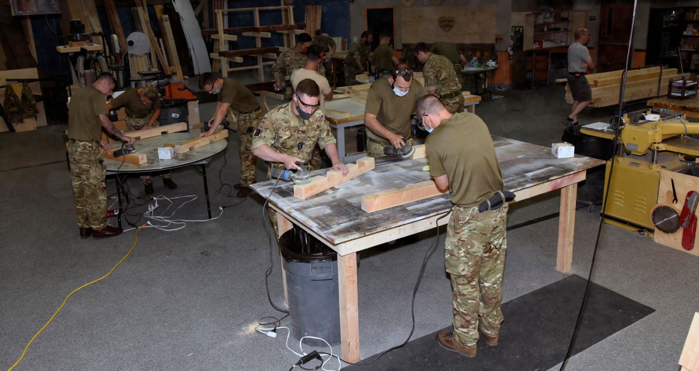 Personnel using woodwork equipment in the workshop. 