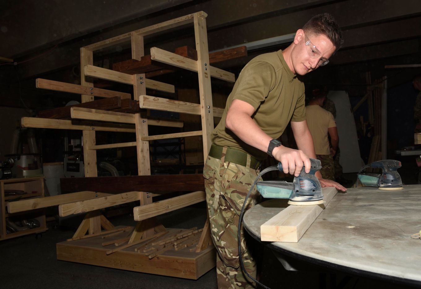 Personnel using woodwork equipment in the workshop.