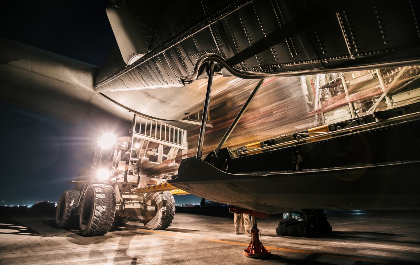 Ground vehicle maintain a C-130J Hercules, lights blur the image.