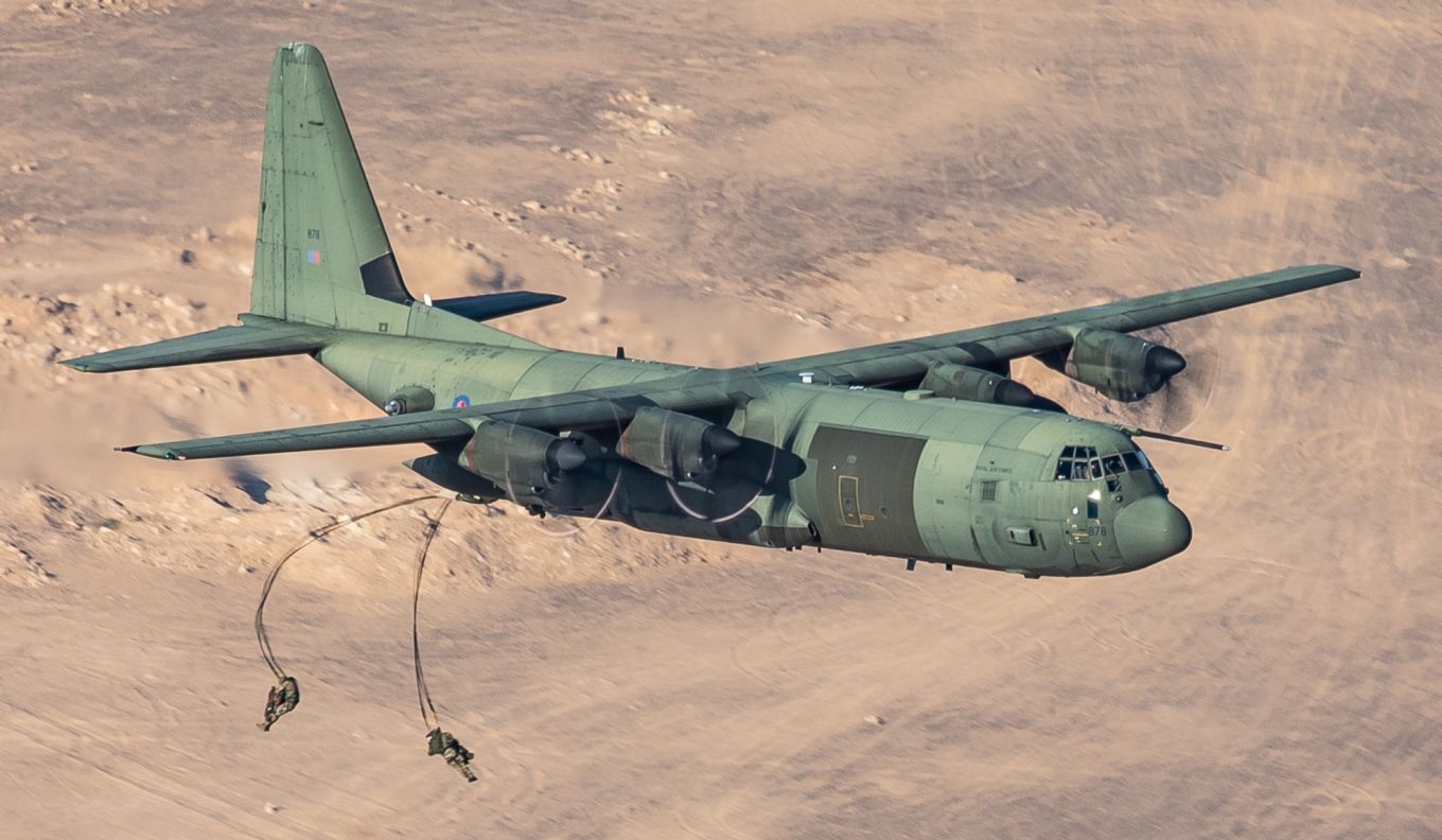 C-130J Hercules aircraft airdrop two parachuting troops.