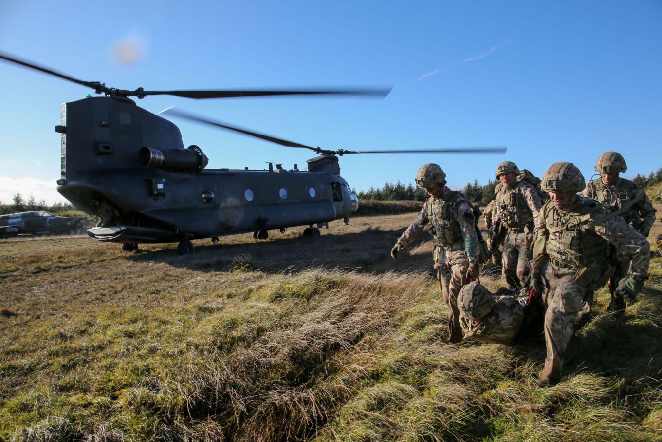 image shows RAF Regiment personnel on the exercise next to a Chinook helicopter.