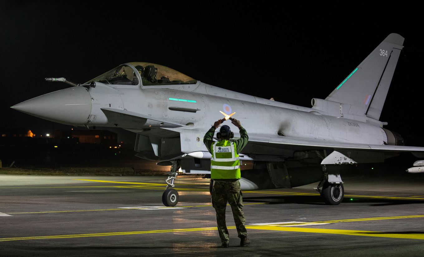 Image shows an RAF typhoon aircraft being guided by a ground steward.