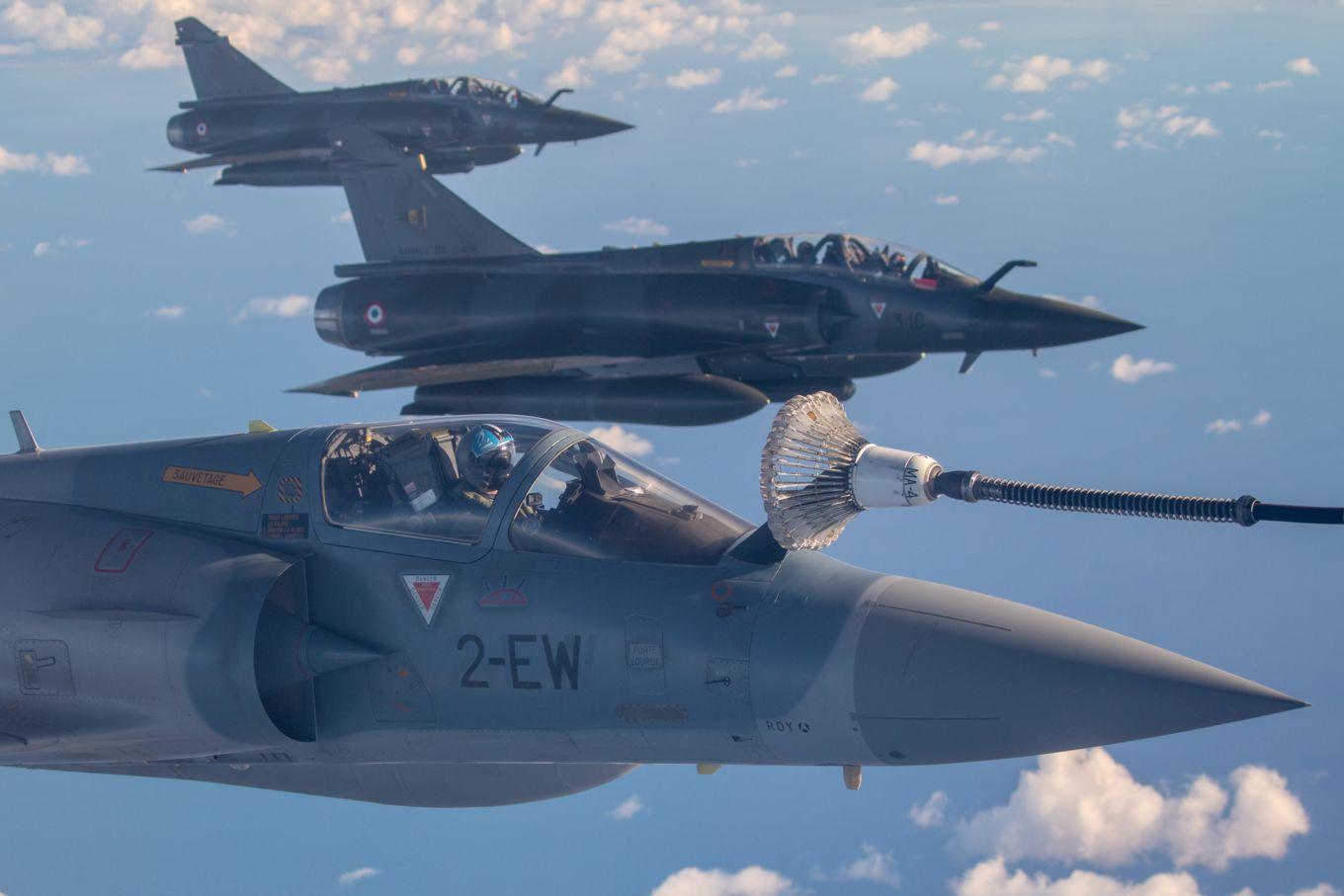 Image shows three French Mirage 2000 aircraft flying while one is being refuelled.