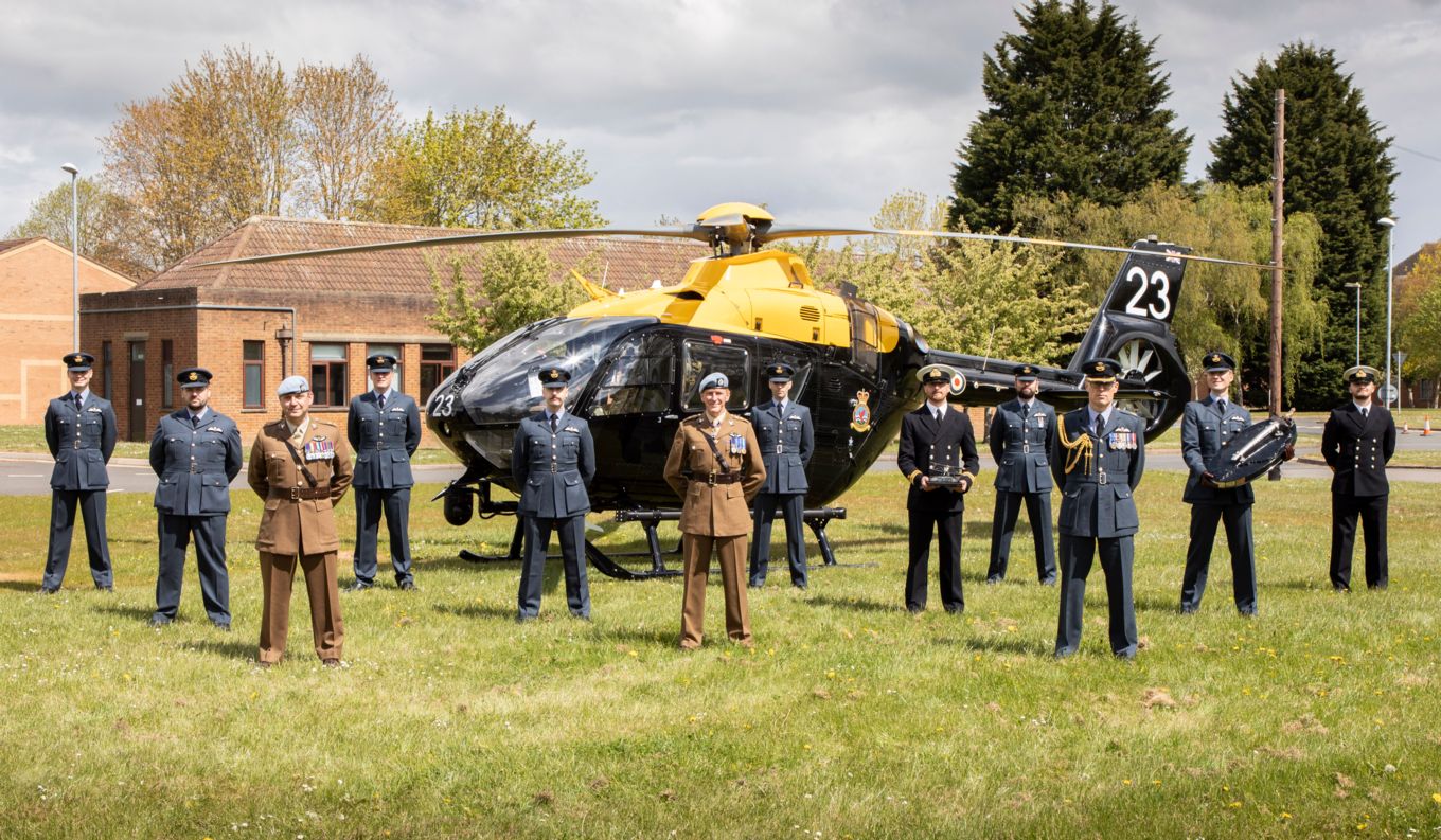 Image shows graduating personnel with Tim Peake in front of a helicopter.