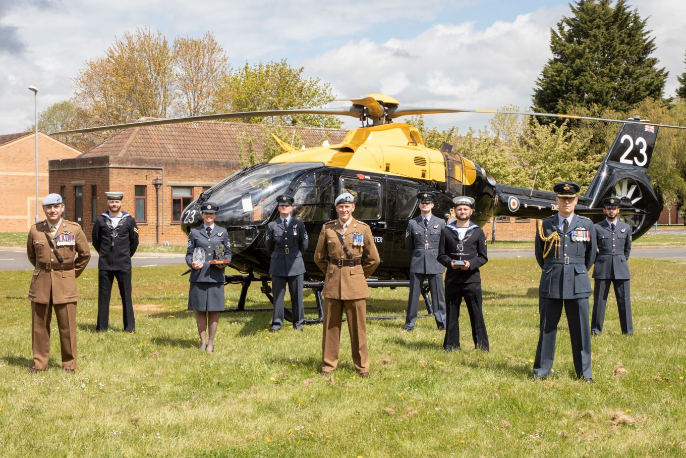 Image shows graduating personnel with Tim Peake in front of a helicopter.