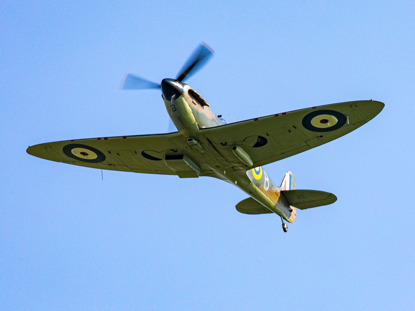 Image shows RAF spitfire flying with blue sky