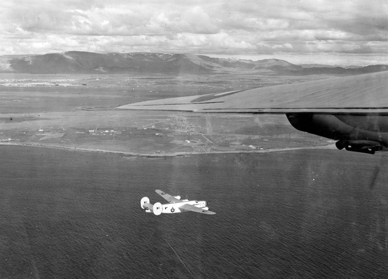 A black and white image showing Consolidated Liberator GR.IIIs flying over the sea.