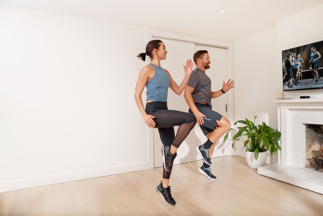 Image shows a man and a women conducting a home workout.